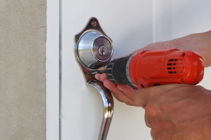 Profesjonell låsesmed installerer dørhåndtak ved hjelp av boremaskin